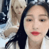 two girls are sitting next to each other in a room and one of them is looking at the camera .