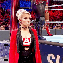a woman is standing in a wrestling ring wearing a red jacket and black top .