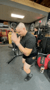 a man squatting in a gym with a sign on the wall that says ' sds '