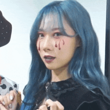 a woman with blue hair and blood on her face