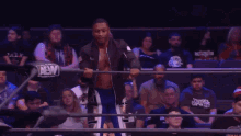 a wrestler is jumping in the air in front of a crowd while wearing a black shirt that says aew