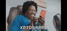 a woman is sitting in a chair laughing while looking at her cell phone .
