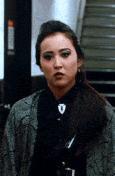 a woman wearing a black shirt and a snake print jacket stands in front of stairs