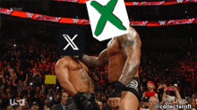 a wrestling match with a green x on the head of one of the men