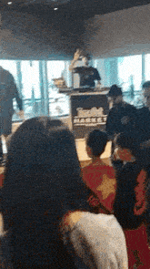 a group of people are sitting in a room watching a man playing a dj set .