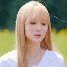 a woman with blonde hair and a white shirt is looking down