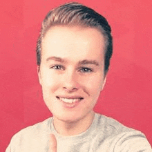 a young man is smiling and giving a thumbs up while taking a selfie .