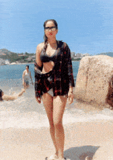 a woman in a bikini stands on a beach