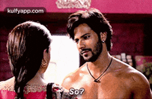 a man without a shirt is talking to a woman in a pink dress .