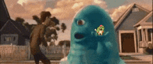 a man is walking down a street next to a blue monster with a bird on it 's head .