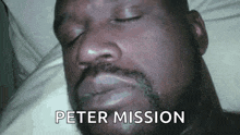 a man with a beard is laying in bed with his eyes closed and the words peter mission written on his face .