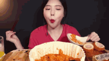 a woman is eating a large bowl of food with chopsticks and a spoon .