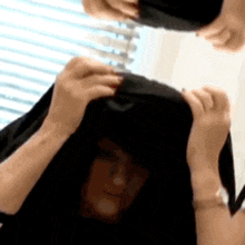 a person is holding a black object in front of a window .
