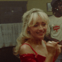 a woman in a red dress is smiling while a man in a coca cola shirt stands behind her