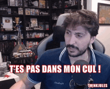 a man sitting in front of a microphone with the words t'es pas dans mon cul written below him