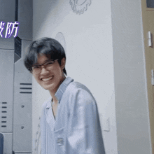 a man wearing glasses is smiling in front of a wall with chinese writing on it