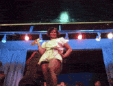 a woman is standing on a stage holding a trophy and smiling