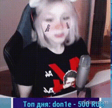 a girl is sitting in front of a microphone wearing a cat ear headset and a black shirt .