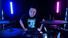a man wearing a black shirt with the letter j on it playing drums