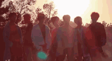 a group of young men are standing in a line in front of a sunset .