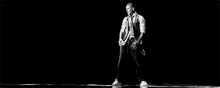 a black and white photo of a man dancing in a room .