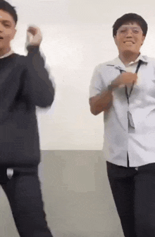 two young men are dancing together in a room in front of a wall .