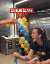 caitlin clark is playing a game with balloons and a basketball in the background