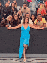 a woman in a blue dress is posing for a photo with a group of people