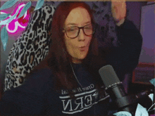 a woman wearing glasses and a sweater that says ' aerie ' on it stands in front of a microphone