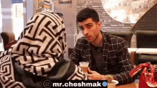 a man and a woman are sitting at a table talking to each other in a restaurant .