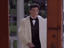 a young man in a tuxedo is standing in a doorway