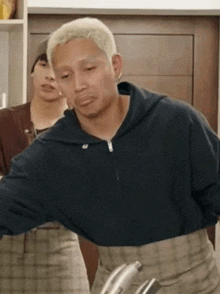 a man with blonde hair is wearing a black hoodie