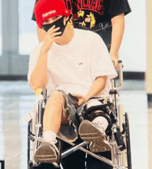a man wearing a red supreme hat is sitting in a wheelchair
