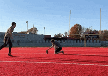 two men playing a game of football on a field with a building in the background