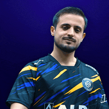 a man with a beard is wearing a blue and yellow shirt with the letter s on the chest