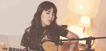 a woman is playing a guitar in front of a microphone