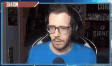 a man wearing glasses and headphones is sitting in front of a microphone .