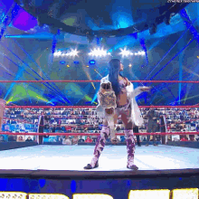 a woman is standing in a wrestling ring holding a stuffed animal