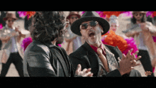 a man in a hat is talking to another man in a suit and tie