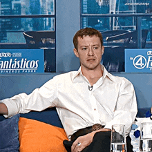 a man sits on a couch in front of a fantasticos sign