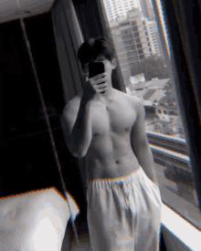 a shirtless man taking a picture of himself in a mirror