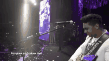 a man is singing into a microphone with a strap that says harmonia