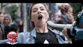 a woman in a denim jacket is holding a large object in her mouth with a red van in the background that says dupa de artist