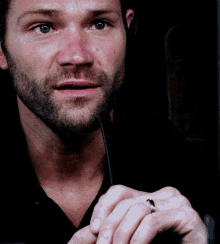 a man with a ring on his finger is looking at the camera
