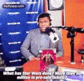 a man wearing headphones is sitting in front of a microphone and talking about star wars .