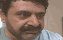 a man with a beard and curly hair is looking at the camera