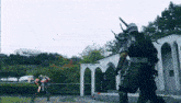 a man in a samurai costume is fighting another man in a samurai costume in a park .