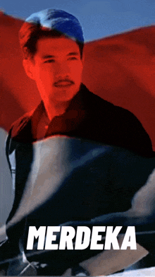 a man stands in front of a red white and blue flag with the word merdeka on the bottom