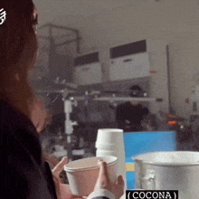 a woman is holding a cup that says cocona