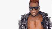 a man with red hair is wearing a black leather jacket with spikes on it .